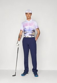 Herrgolfoutfit med en ljuslila pikétröja med landskapsmönster, marinblå byxor, vitt skärp och skor med blå detaljer. Accessoarer inkluderar en keps och en golfklubba.