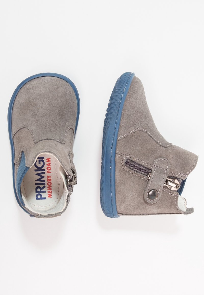 Bottines pour enfants en daim gris avec semelles en caoutchouc bleu et fermetures éclair latérales, une botte montrée de dessus et l’autre de côté.