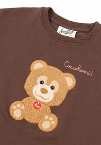 Felpa marrone con un design di orsetto ricamato a rilievo con zampette e la scritta "Coccolami!" in rosa sopra l'orsetto.