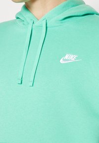 Mintgröna hoodien är tillverkad av mjukt tyg och har en framficka, dragsko på huvan samt en vit Nike-logotyp på bröstet.