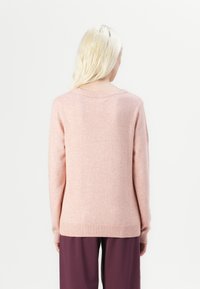 Pull en tricot rose clair avec encolure et poignets côtelés, coupe décontractée et texture douce, vu de dos.