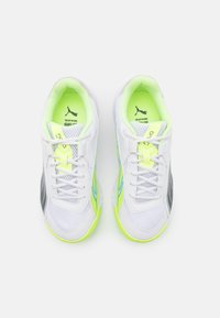 Zapatillas deportivas blancas con materiales de malla y sintéticos, que presentan acentos en verde neón, paneles laterales grises y cordones blancos. Diseño ligero.