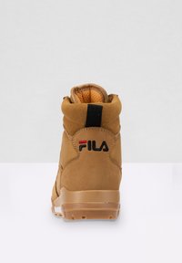 Bottine en suède marron et mesh avec un col rembourré, semelle en caoutchouc et logo FILA noir et rouge sur le talon.