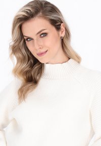 Kremfarvet ribbet sweater med høj hals. Blød tekstur, tætsiddende design og diskrete detaljer forbedrer det samlede udseende.