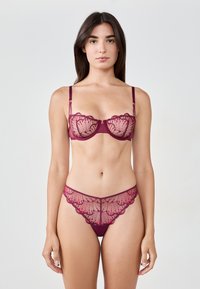 Conjunto de lencería de encaje burdeos con delicados bordados florales, paneles transparentes, sujetador con aros y tanga a juego con bordes festoneados.