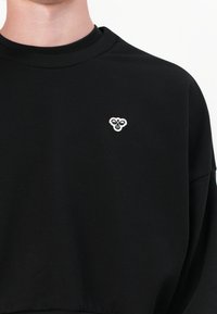 Black sweatshirt made of cotton, featuring a ribbed neckline and a small white logo on the left chest. Soft texture, relaxed fit.