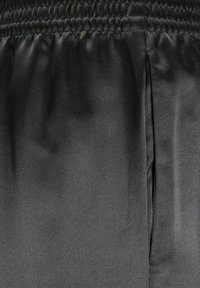 Black satin fabric with a smooth texture, featuring an elastic waistband and a seam detail along the side. No notable patterns or accents.