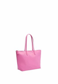 Sac fourre-tout en cuir rose avec de longues poignées, forme rectangulaire, fermeture à glissière et un petit logo sur le devant. Texture lisse, design minimaliste.