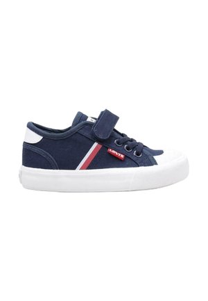 Zapatilla de lona azul marino con suela de goma blanca, franjas rojas y blancas, que cuenta con una combinación de correa de velcro y cordones para el cierre.