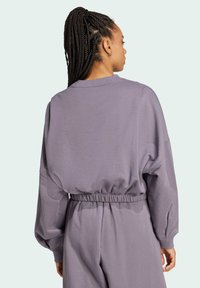 Felpa viola oversize con collo a giro ribbed, vita elastica e spalle scese. Realizzata in tessuto morbido e texturizzato.