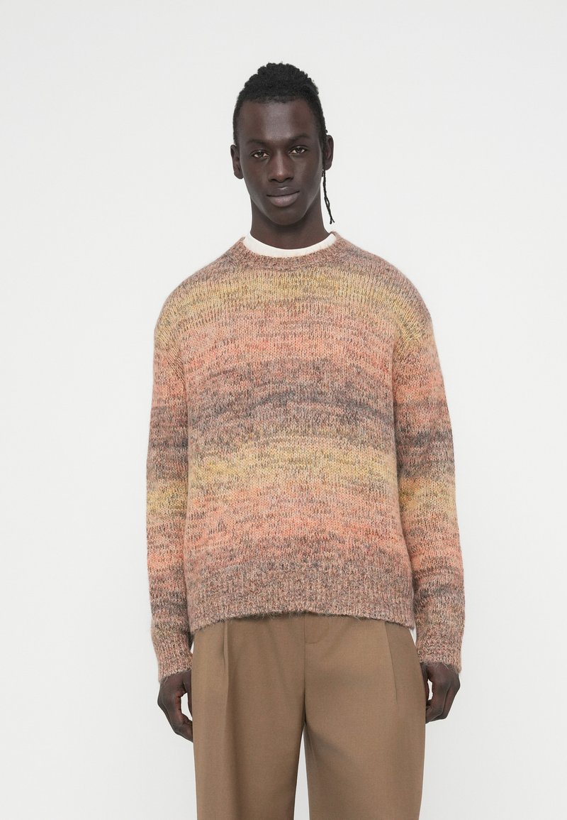 Πλεκτό πουλόβερ σε γήινες αποχρώσεις ροδάκινου, καφέ και κίτρινου, με στρογγυλή λαιμόκοψη και χαλαρή εφαρμογή. Υφή υφάσματος με οριζόντια διαβάθμιση.