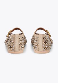 Scarpe beige in suede con strass decorativi. Apertura sul retro con una fascetta e fibbia in tono oro. Suola piatta con leggera imbottitura.