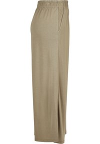Jupe longue beige avec taille élastique et poche latérale, en tissu doux, vue de profil sur fond blanc.