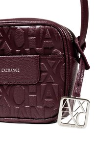 Borsa a tracolla sintetica bordeaux con texture, logo impresso, tracolla regolabile e dettagli metallico con logo.