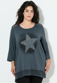 Mørkegrå t-shirt med rund halsudskæring og 3/4-ærmer. Har et stort stjernedesign lavet af rhinsten og en tekstureret, delt kant.