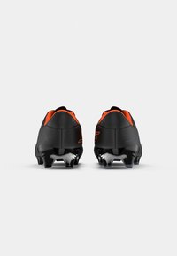 Black football boots with orange accents, featuring a sleek design, low-profile shape, textured upper, and black studded outsole.