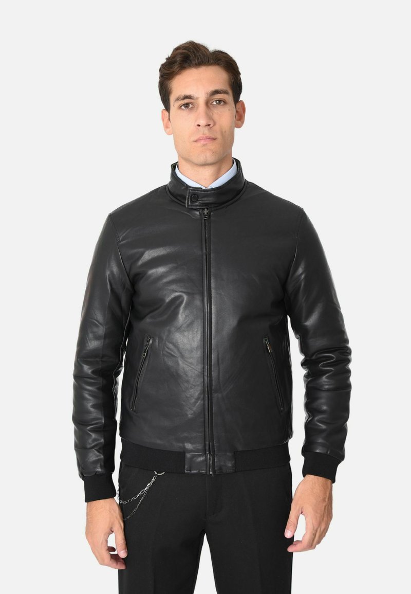 Giacca in pelle nera con colletto alto, chiusura con zip frontale e polsini a coste. Presenta due tasche laterali e una texture liscia e lucida.