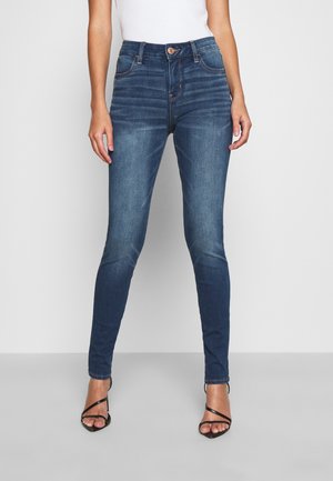 Jeans ajustados de talle alto en denim azul oscuro con una textura suave, que cuentan con un cierre de botón y detalles de costura mínimos.