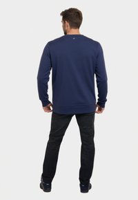 Sudadera azul marino de manga larga, con cuello redondo y puños de canalé. Fabricada en una tela suave, con una textura sutil y sin logotipos visibles.