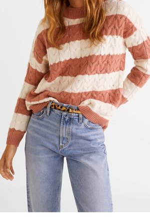 Femme portant un pull torsadé rayé rose et blanc, rentré dans un jean taille haute bleu clair avec une ceinture imprimé léopard.