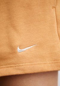 Narancssárga pamut rövidnadrág, texturált felszínnel, a szegély közelében egy kicsi, fehér hímzett Nike logóval.