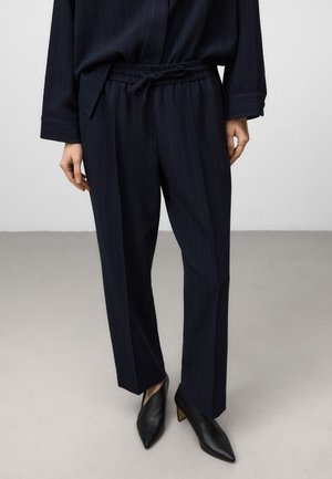 Navy gemusterde broek met een trekkoord in de taille, textuurstof en rechte pijpen, gecombineerd met zwart puntige hakken.