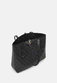 Black patterned tote bag with a textured surface, gold hardware, and two long straps. Open top with a spacious interior.