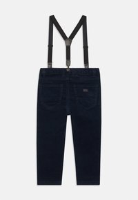Dark blue corduroy pants with adjustable black suspenders, featuring two back pockets and a button closure at the waistband.