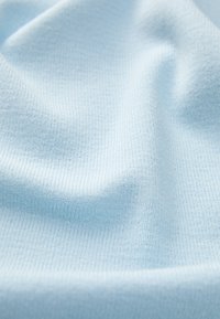 Tecido texturizado azul claro com um padrão estriado, apresentando uma aparência suave e macia, adequado para vestuário ou estofos.
