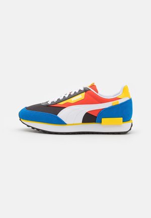 Mehrfarbige Sportschuh mit einer Mischung aus schwarzen, roten, blauen und gelben Materialien. Netz- und Wildledertexturen mit weißen Akzenten und Schnürsenkeln.
