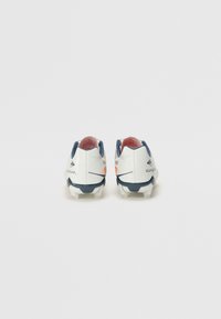 Botas de fútbol blancas con acentos en navy y rojo, que presentan un diseño texturizado, una suela contrastante y un tacón redondeado.
