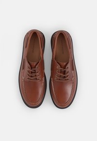Chaussures en cuir marron avec une finition lisse, bout arrondi, design à lacets et couture contrastante. Les semelles en caoutchouc offrent un soutien durable.