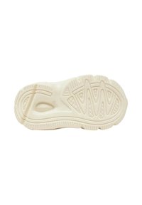 Suola delle scarpe in bianco sporco con modelli di presa testurizzati. Presenta bordi arrotondati e scanalature superficiali per aderenza e flessibilità.