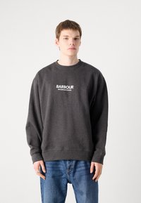 Tmavě šedá mikina s kulatým výstřihem a dlouhými rukávy. Na přední straně je bílý nápis "BARBOUR INTERNATIONAL". Kombinováno s modrými džíny.
