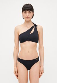 Juodas vienšalis bikini viršus su išpjova ir rišama petneša; derančios juodos bikini kelnaitės su subtiliu auksiniu akcentu ant juosmens.