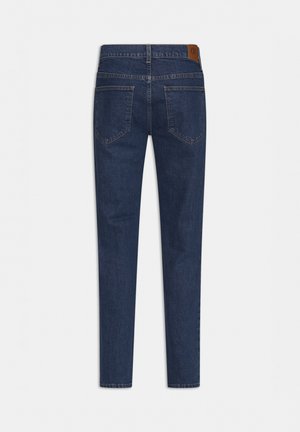 Granatowe dżinsy z prostymi nogawkami. Cechy to dwie tylne kieszenie, widoczne przeszycia oraz brązowa skórzana metka w talii.