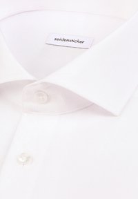 Col de chemise blanche en tissu et premiers boutons avec une étiquette "seidensticker" visible à l'intérieur du col au niveau du dos.