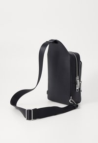 Black faux leather bag with a rectangular shape, zip closures, a flat strap, and a smooth texture. Silver hardware accents are present.