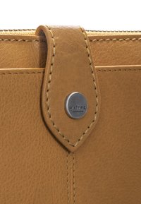 Tan leather wallet with a textured surface, featuring a stitched flap and a metal snap button with "MAITRE" engraved.