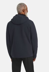 Felpa con cappuccio a coste blu navy, dotata di un grande cappuccio morbido e di una vestibilità rilassata. Presenta un tessuto testurizzato ed è abbinata a pantaloni neri.