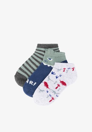 Tres pares de calcetines para niños pequeños hasta el tobillo: uno con rayas grises y verdes, uno azul con la cara de un tiburón y texto "¡RAWR!", y uno blanco con estampados de dinosaurios en rojo y azul.
