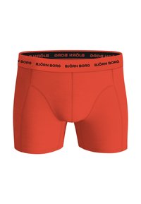 Rote Boxershorts mit einem schwarzen elastischen Bund, der mit wiederholt aufgedrucktem "BJÖRN BORG"-Schriftzug versehen ist. Aus dehnbarem, glattem Stoff gefertigt.