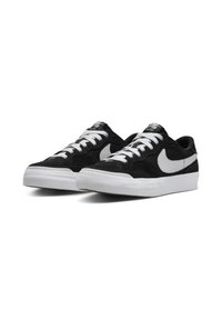 Fekete velúr sportcipők fehér fűzős és swoosh logóval, vastag fehér gumitalppal és puha szövet textúrával.