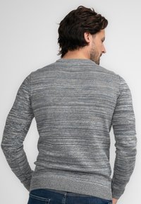 Grauer, strukturierter Pullover mit einem dezenten Muster, Rundhalsausschnitt und gerippten Bündchen und Saum. Sichtbare Nähte auf der Rückseite.