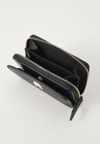 Zwarte leren portemonnee met een ritssluiting, gouden hardware en meerdere compartimenten. Het interieur heeft een zachte textuur en een zwarte voering.