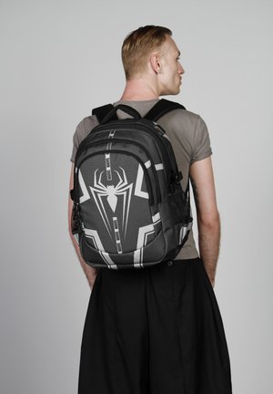 Mochila temática de Spider-man en negro y gris con un patrón hexagonal, un prominente logo de araña, múltiples compartimentos y correas ajustables.