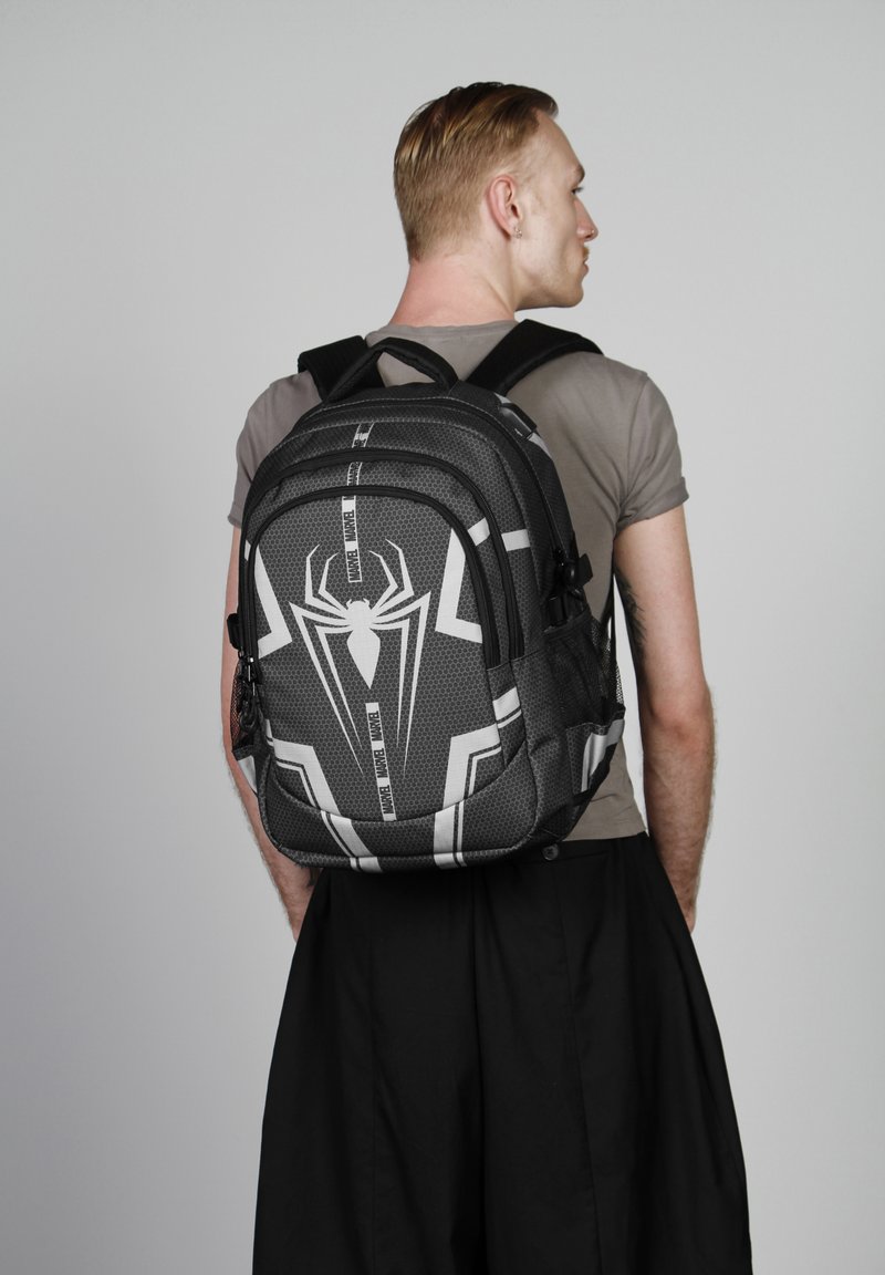 Sac à dos sur le thème de Spider-man, noir et gris, avec un motif hexagonal, un logo de spider bien en évidence, plusieurs compartiments et des bretelles réglables.