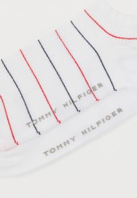 Λευκές βαμβακερές κάλτσες με κόκκινες και ναυτικές ρίγες, με το "TOMMY HILFIGER" τυπωμένο ασημί στο πλάι. Ριμπ υφή στη μανσέτα.