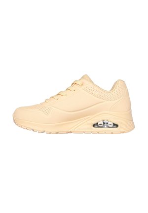 Light beige sneakers with a smooth, textured surface, lace-up design, perforated accents, and a visible air cushioning unit on the sole.