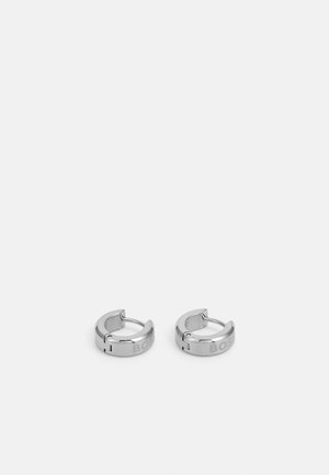 Orecchini a cerchio in argento con una finitura lucida, caratterizzati da un design senza soluzione di continuità e una discreta incisione del marchio. Forma rotonda con chiusura a cerniera.